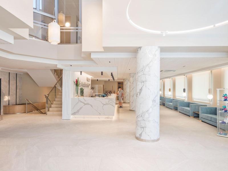 Světlé, moderní hotelové lobby s mramorovými prvky, recepcí a pohodlnými sezeními.