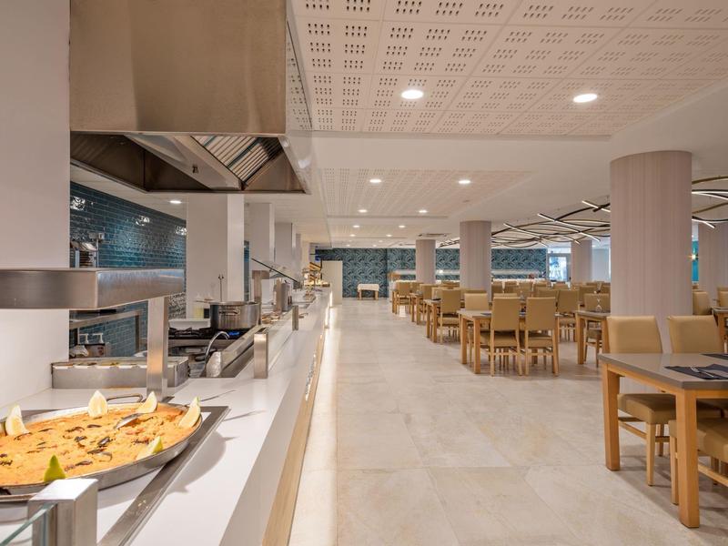 Jasně zařízená jídelna s bufetem a dřevěnými stoly v moderním hotelu.