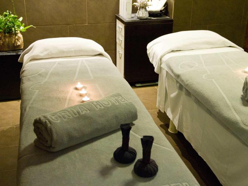 Zwei Massageliegen mit weißen Handtüchern in einem warm beleuchteten, ruhigen Raum.