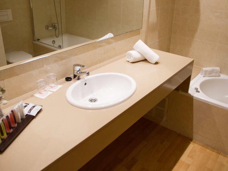 Moderner Badezimmertresen mit rundem Waschbecken, Spiegel, Handtüchern und Whirlpool-Badewanne.