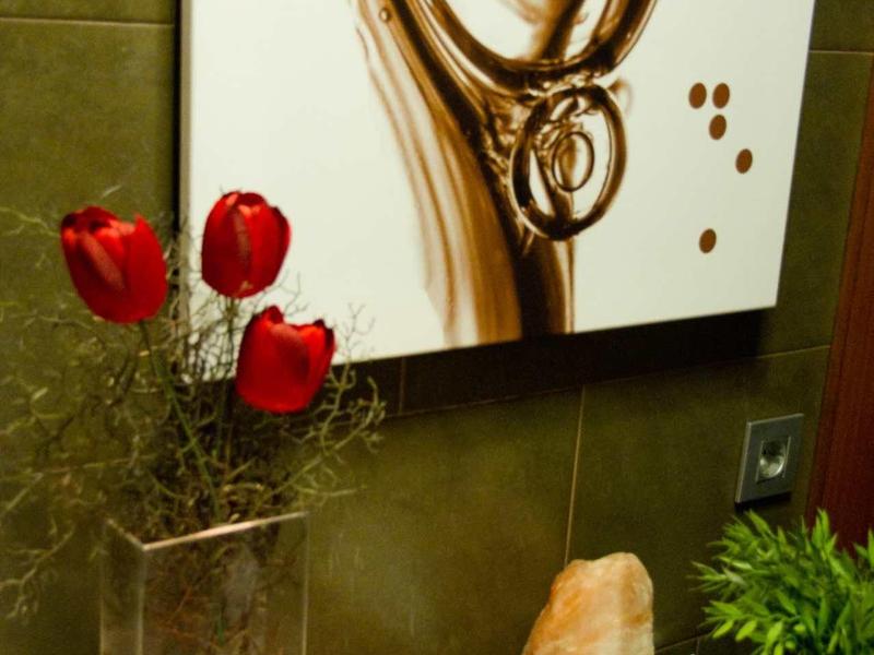 Rote Tulpen in Glasvase, Bilderrahmen, grüner Topf und ein Bild mit goldfarbenem Muster an Wand.