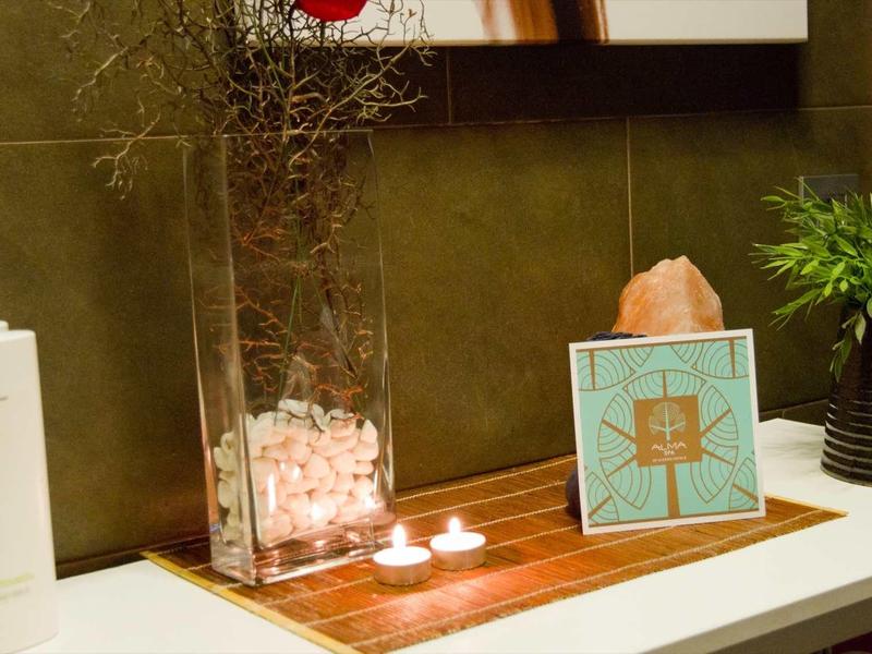 Moderner Badezimmerschrank mit Duftkerzen, Seifenspender, Pflanzen und dekorativem Salzstein.