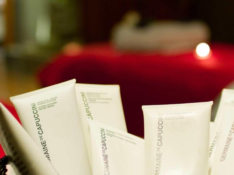 Weiße Tuben in einem Korb, unscharfer Hintergrund mit rotem Stoff und Kerzenlicht.