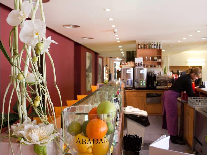 Moderner Café-Innenraum mit Obstglas, hängenden Blumen und Kaffeetheke im Hintergrund.