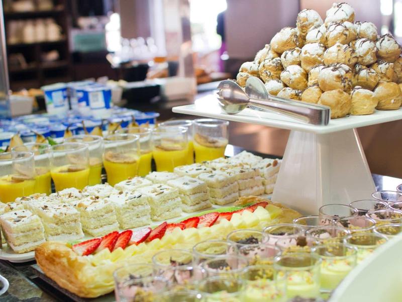 Vielfalt an Desserts mit Sahnetörtchen, Pudding und Fruchtjoghurt auf Buffet in heller Umgebung.