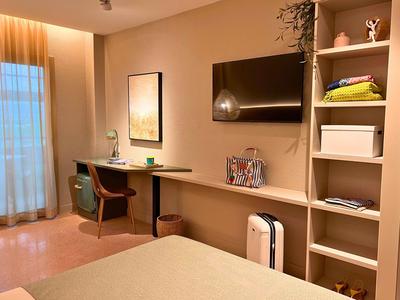 Modern workspace in hotel room with desk, chair, and wall-mounted TV.