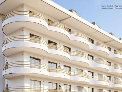 Modern multi-story hotel building with curved balconies and white facades in daylight.