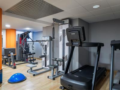 Modern hotel gym with treadmill, strength machines, and colorful workout equipment.