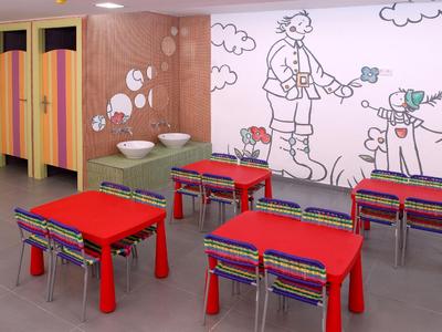 Children's playroom with colorful tables, chairs, and comic wall art