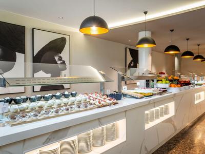Large buffet with varied dishes and warm lighting in a modern dining area.