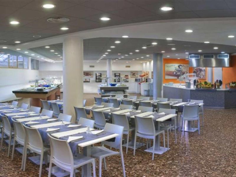 Moderní jídelna s bílými židlemi a stoly v hotelu.