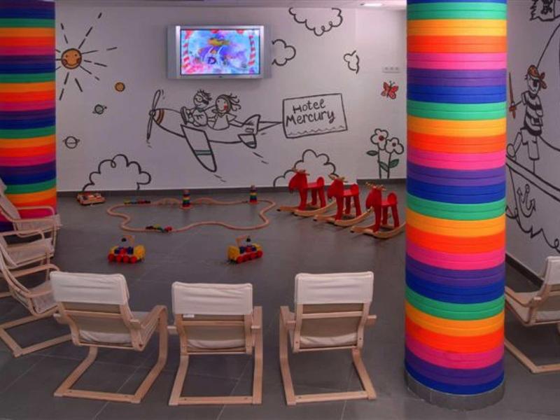 Barevná seminární místnost s dřevěnými židlemi, malovanými stěnami a obrazovkou na zdi.