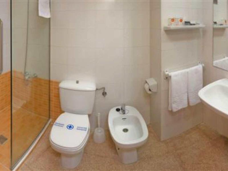 Kompaktní koupelna se sprchou, toaletou, bidetem a umyvadlem v neutrálních tónech.