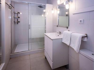 Moderní koupelna se sprchou, umyvadlem, zrcadlem a ručníky v hotelovém pokoji.