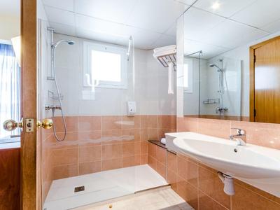 Helles Badezimmer mit großer Dusche, weißem Waschbecken, braunen Fliesen und Spiegelfront.