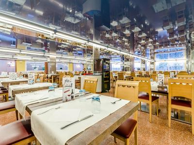 Großer, heller Speisesaal mit Reihen von Tischen und Stühlen, gedeckt mit weißen Tüchern.