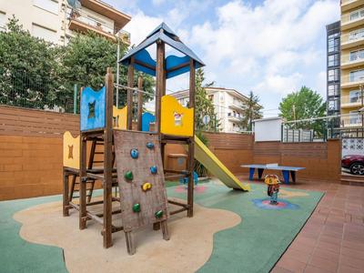 Kinderspielplatz mit Klettergerüst, Rutsche und Federtier, umgeben von Wohngebäuden.