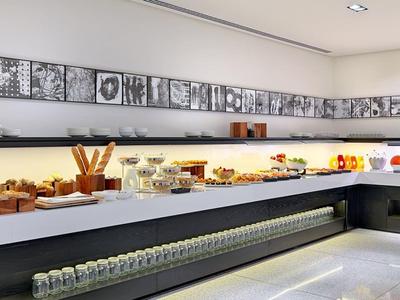 Modern breakfast area with a long counter, pastries, and coffee machines.