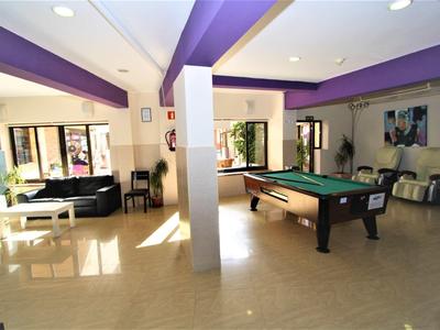 Jasna sala rekreacyjna z fioletowymi belkami na suficie, stołem bilardowym i miejscami do siedzenia.