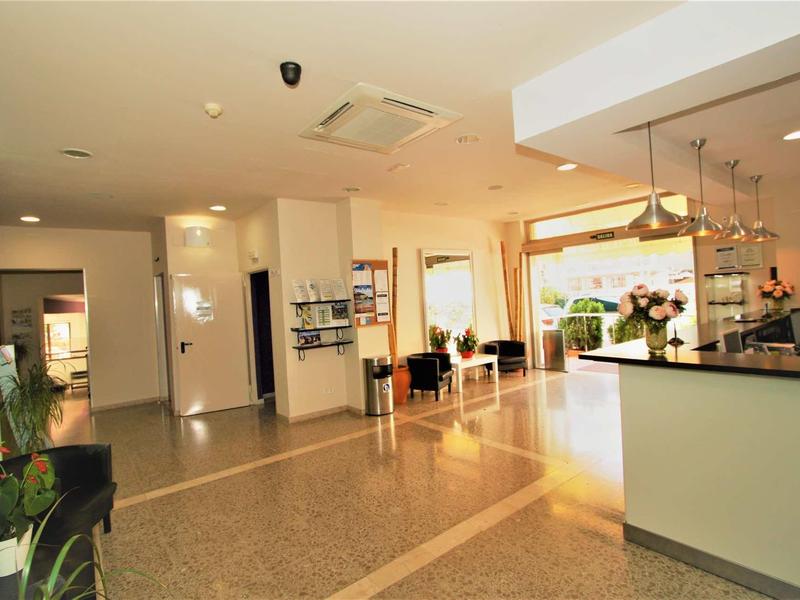 Jasna recepcja hotelowa z bufetem, miejscami do siedzenia i roślinami.
