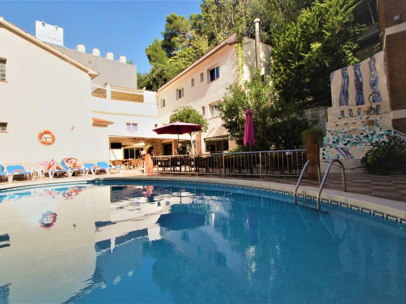 Zapraszający basen z leżakami, parasolami i budynkami w tle.