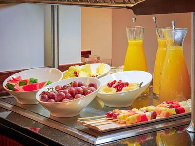 Table avec bols de fruits frais, pichets de jus et brochettes de fruits pour le petit-déjeuner.