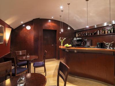 Intérieur de bar confortable avec mobilier en bois, plafond voûté et lampes suspendues.