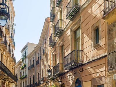 Enge Pflasterstraße mit historischen Gebäuden und blauen Türen bei klarem Himmel.