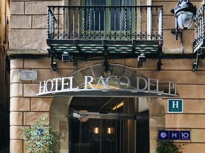 Eingang eines Hotels mit Balkon und Pflanzen in Töpfen auf beiden Seiten.