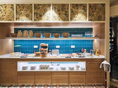 Modern eingerichteter Frühstücksbereich mit blauer Kachelwand und Holzmöbeln.