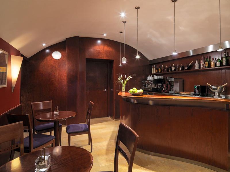 Intérieur de bar confortable avec mobilier en bois, plafond voûté et lampes suspendues.