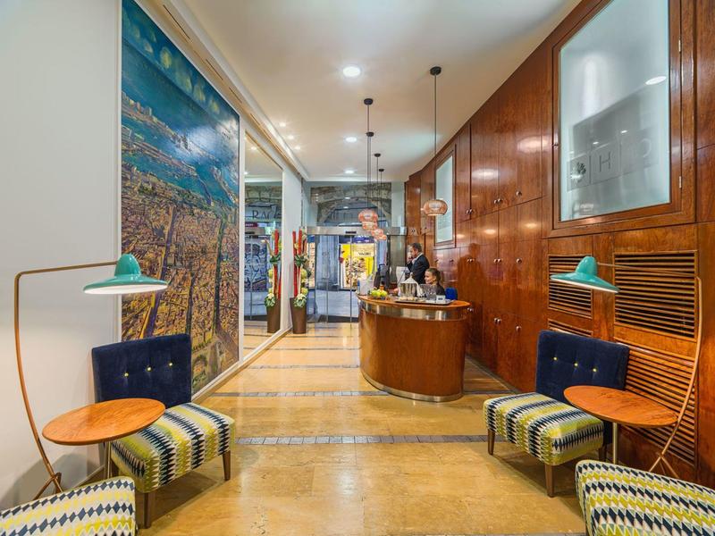 Réception d'hôtel moderne avec comptoir, fauteuils confortables et décoration murale.