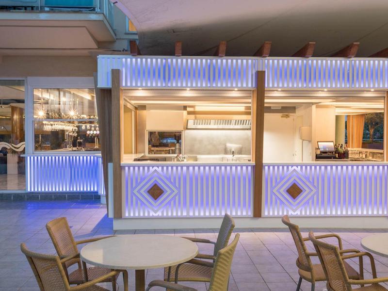 Bar esterno moderno con illuminazione d'atmosfera e area salotto in cortile d'hotel.