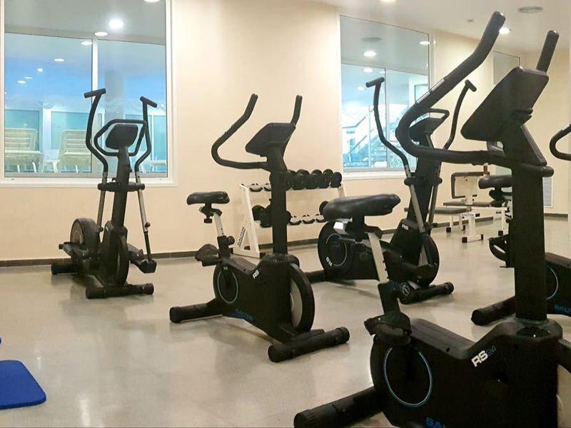 Palestra moderna con cyclette e tappetini yoga in una stanza luminosa con grandi finestre.