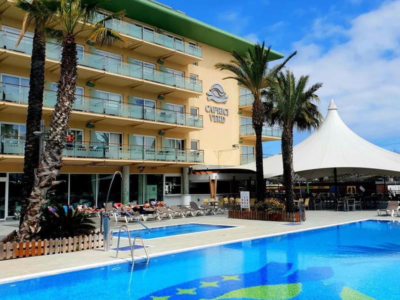 Hotel con piscina, palme e cielo azzurro sullo sfondo.