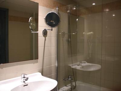 Salle de bain moderne avec douche en verre, évier blanc et grands miroirs.