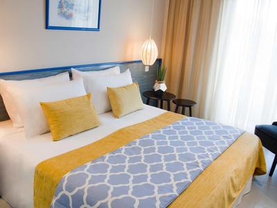 Chambre d'hôtel moderne avec lit double, accents jaunes et deux lampes de chevet.