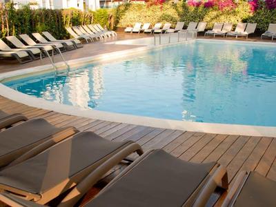 Une piscine extérieure calme avec des chaises longues sur une terrasse d'hôtel