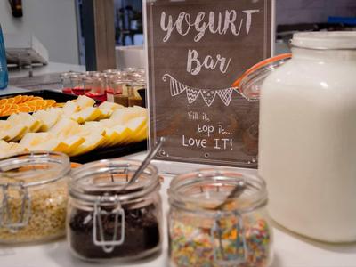 Bar à yaourt avec différents garnitures et un grand pot de lait sur un comptoir.