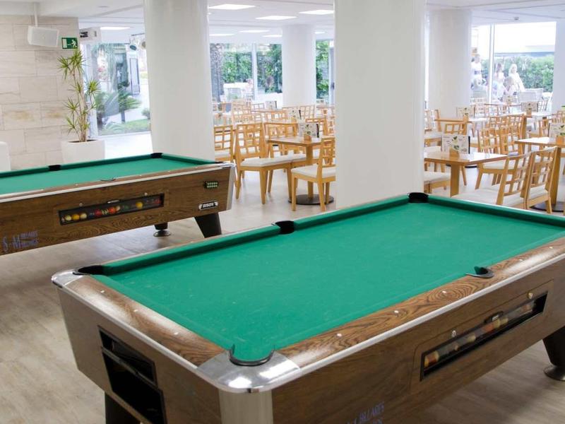 Intérieur avec tables de billard dans une salle de loisirs lumineuse et moderne avec colonnes blanches et chaises en bois