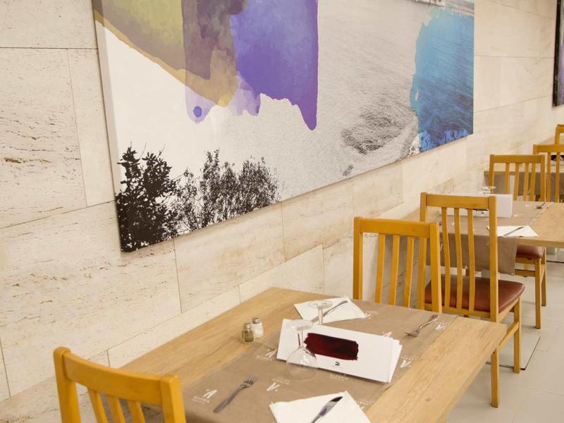 Espace repas moderne avec tables et chaises en bois le long d'un mur en pierre avec une œuvre colorée