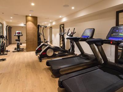 Palestra moderna con tapis roulant, ellittiche e specchi con luce calda.