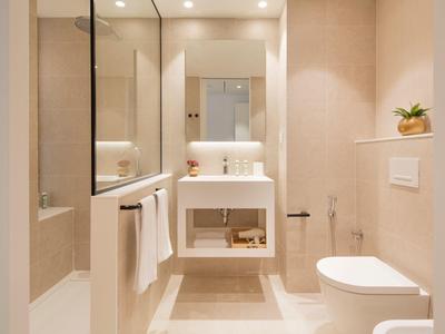 Jasna nowoczesna łazienka z umywalką, toaletą i podświetlanym lustrem.