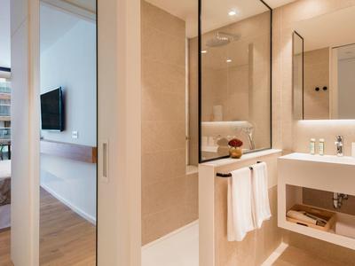 Łazienka z umywalką, lustrem i ręcznikami obok sypialni.