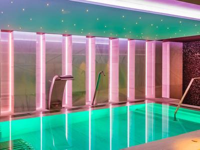 Nowoczesny basen kryty z zielonym oświetleniem i relaksującą atmosferą w hotelu.
