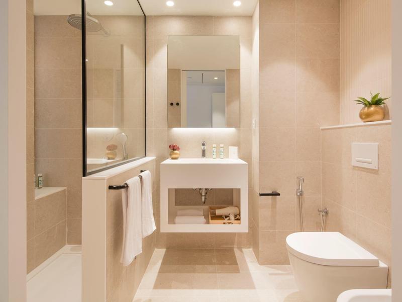 Jasna nowoczesna łazienka z umywalką, toaletą i podświetlanym lustrem.