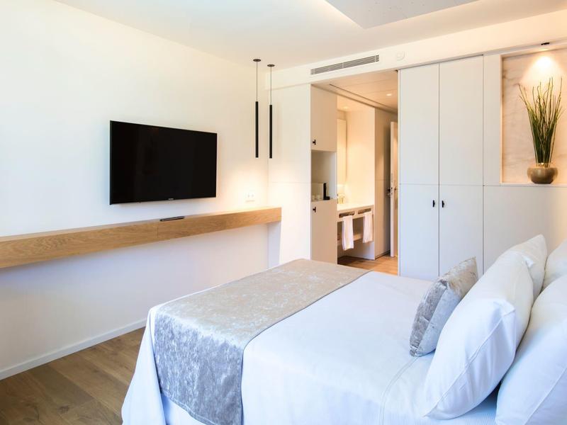 Nowoczesny pokój hotelowy z podwójnym łóżkiem, telewizorem na ścianie i widokiem na łazienkę