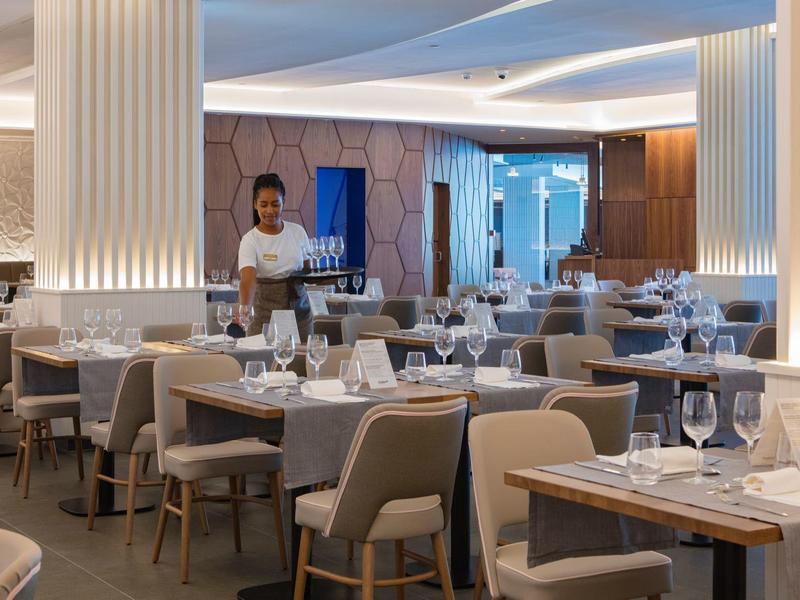 Nowoczesna restauracja z elegancko nakrytymi stołami i kelnerką przy stole.