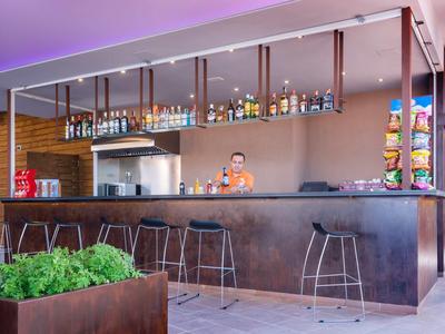 Nowoczesny bar hotelowy z hokerami, wyborem napojów i rustykalną atmosferą.