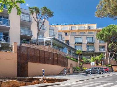 Nowoczesny budynek hotelu z tarasem i drzewami pod czystym niebem.